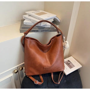 Detail showing vintage brown faux leather texture and plush bear charm on the tote bag