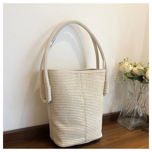 Close-up of woven bucket bag texture with smooth leather handle on a wooden surface