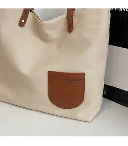 Dettaglio della borsa tote in tela con tasca in pelle marrone e cuciture rinforzate