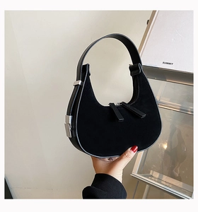 Detail of black suede crescent bag featuring silver hardware and dual zippers
