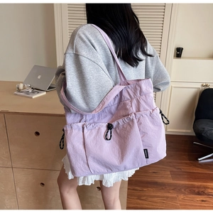 Purple nylon tote bag with drawstring pockets shown in a casual lifestyle setting