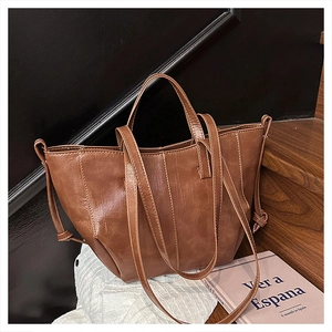 Close-up of brown vintage leather tote bag with stitching details and long strap