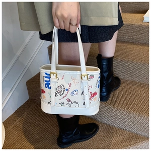 Détail du sac cabas en cuir blanc avec graffitis colorés et boucles dorées sur les anses