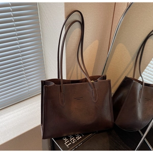 Detailed view of dark brown vintage leather tote bag with embossed fashion text and long straps