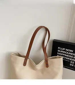 Dettaglio della borsa tote in tela beige con tracolla in pelle marrone e rivetti metallici