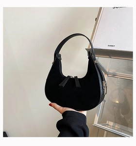 Detailed shot of black matte suede hobo bag with silver zipper in a minimalist aesthetic