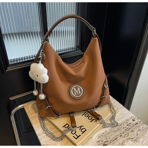 Dettaglio della borsa tote marrone vintage con logo M in metallo e ciondolo a nuvola