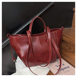 Detailed close-up of a vintage dark red tote bag with shiny wrinkled texture on stairs