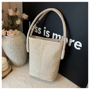 Detail of hand-woven bucket bag featuring a premium beige leather handle and smooth texture