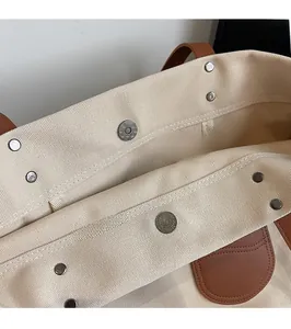 Dettaglio della borsa tote in tela beige con chiusura magnetica e manici in pelle