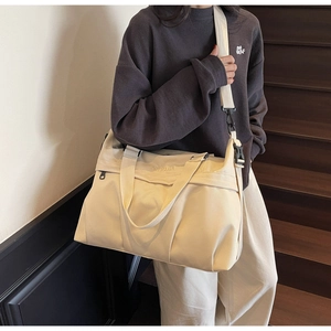 Dettaglio della grande borsa tote in tela beige con tracolla regolabile e manici fissi
