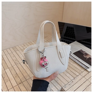 Detail of white PU leather handbag with pink heart and silver key metallic charms