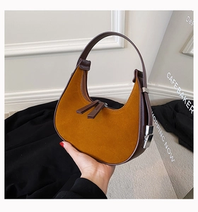 Detail of hobo bag featuring ginger suede texture with dark brown leather piping and handle