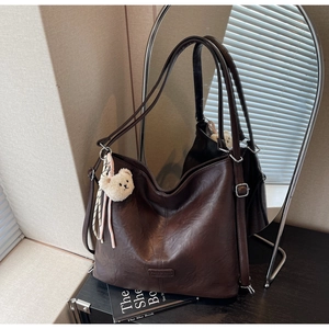 Detail view of large chocolate brown tote bag in vintage oiled leather with teddy bear charm
