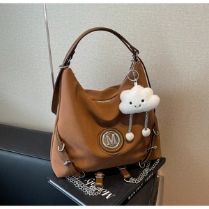 Dettaglio borsa hobo caramello con logo M argento e ciondolo a nuvola di peluche