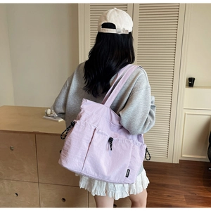 Detail of light purple nylon tote bag with drawstring pockets in a cozy interior setting