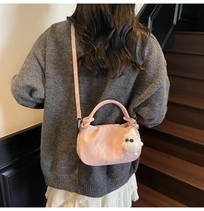 Detail of pink ruched cloud bag with cute white pompom charm and logo on bag bottom