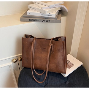 Detail of vintage brown tote bag with pleated leather texture on a velvet bench