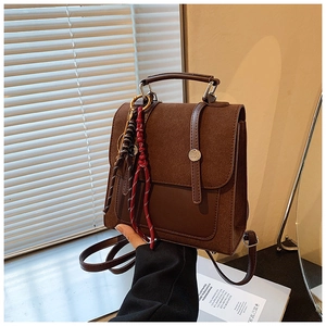 Detail of vintage brown backpack featuring buckle closure and colorful woven charm