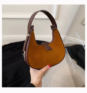Detailed close-up of camel suede underarm bag with dark brown leather trim and dual zippers