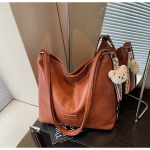 Detail of caramel brown large hobo bag with teddy charm and soft matte leather texture