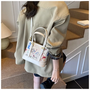 Détail du sac à main en cuir PU blanc avec imprimés graffiti et garnitures métalliques dorées