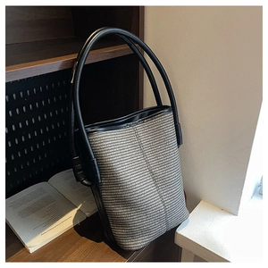 Detailed texture of woven bucket bag next to books with elegant leather handle