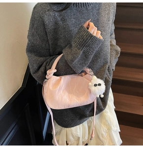 Detail of pink pleated cloud bag with knotted handle and white furry monster charm
