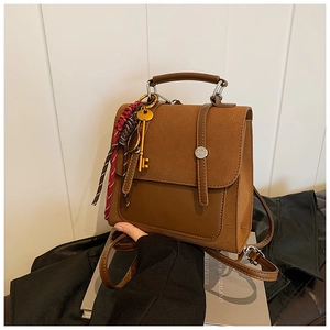 Detail of vintage brown suede backpack with top handle and decorative key charms