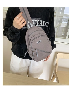Detail of grey canvas crossbody bag with MACHUGE label and functional multi-pocket design