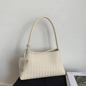 Dettaglio della borsa a secchiello intrecciata beige con ciondolo triangolare elegante