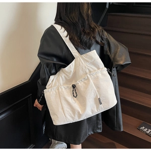 Detail of white nylon tote bag with functional drawstring pockets and wide shoulder strap