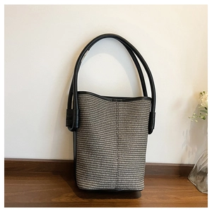 Detail of woven bucket bag featuring black and white texture with leather handle