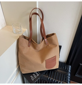 Vista dettagliata della borsa tote in tela kaki con tasca in pelle su valigia da viaggio