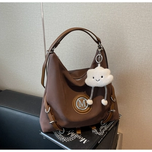 Dettaglio della borsa hobo marrone vintage con logo M in metallo e ciondolo a nuvola