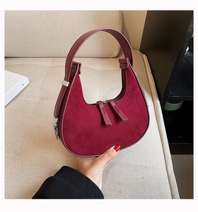 Detail view of burgundy suede crescent bag with dual silver zippers and leather handle