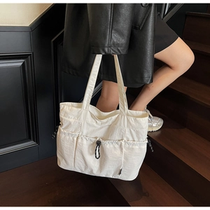 Detailed view of white multi-pocket nylon tote bag with functional drawstring pockets
