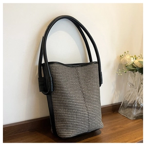 Close-up of woven bucket bag texture with premium black leather trim and handle details
