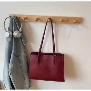 Close-up of deep red tote bag with vintage leather texture and long shoulder straps