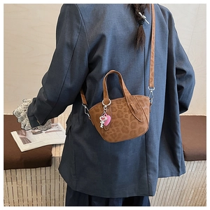 Close-up of leopard print mini crossbody bag with a pink heart charm and shoulder strap