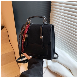 Close-up of black dual-use backpack with matte texture, metal buckles and braided charms