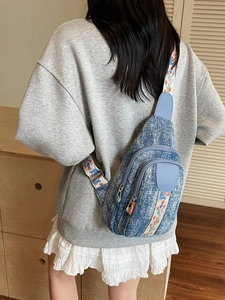 Blue denim crossbody chest bag with floral embroidery and adjustable wide shoulder strap