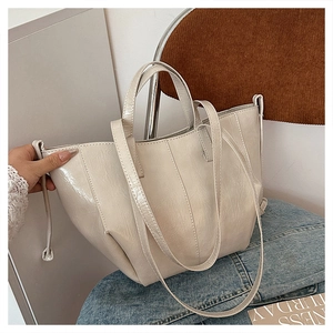 Close-up of cream tote bag featuring shiny wrinkled leather and drawstring details