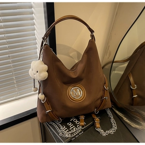 Dettaglio borsa hobo marrone scuro con logo M in metallo e ciondolo a nuvola di peluche
