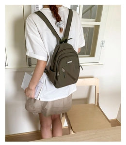 Olive green waterproof nylon mini backpack shown from a rear perspective on a model