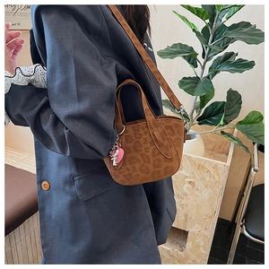 Detail of leopard print crossbody bag with a pink heart charm and brown suede texture