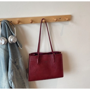 Detail of burgundy tote bag with vintage leather texture and embossed fashion logo