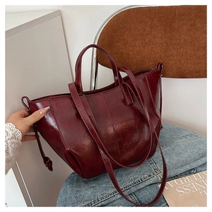 Detail of burgundy wax leather tote bag showing side drawstring and soft pleated texture