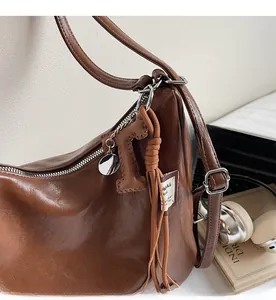 Gros plan d'un sac en cuir PU marron avec fermeture éclair argentée et gland tressé