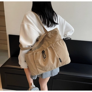 Detail of khaki nylon tote bag showing side pockets and drawstring closure on shoulder bag